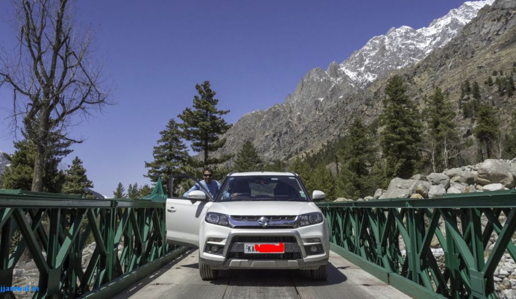 G posing with his car on a bridge near Chitkul